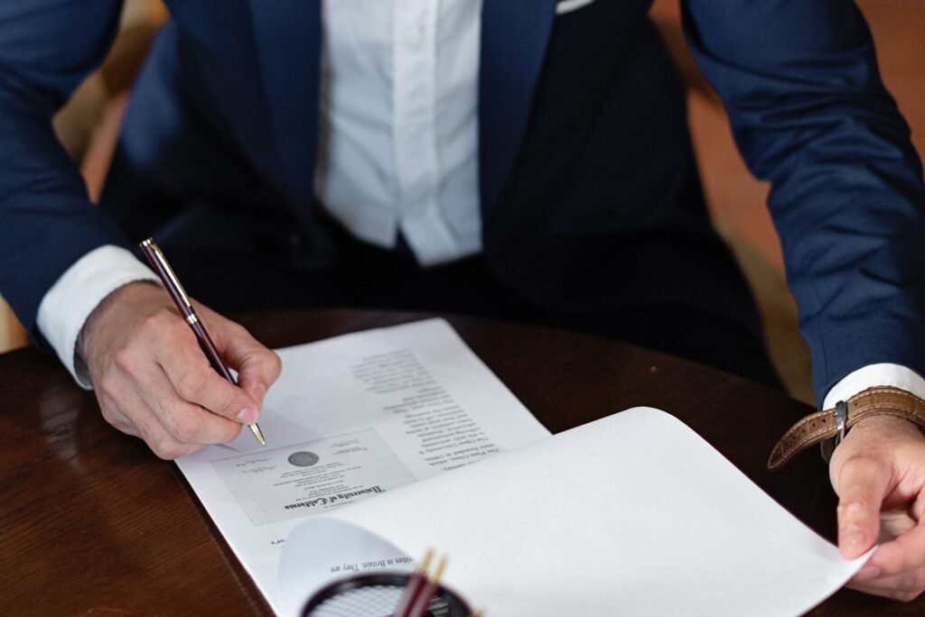 Pessoa assinando documentos em uma mesa de escritório