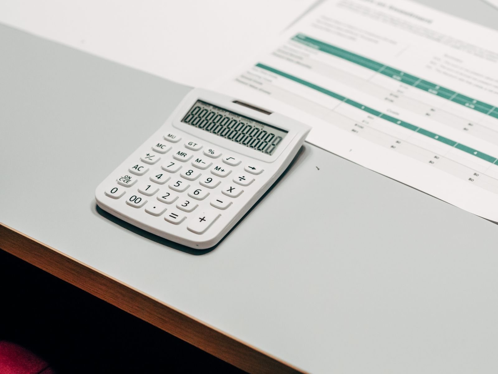 Calculadora ao lado de planilha financeira sobre uma mesa